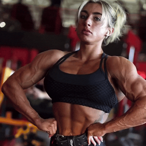 Female bodybuilder flexing defined forearms, abs, and upper body muscles in a gym. Fitness GIF highlighting forearm muscle development, grip strength, and upper body conditioning.