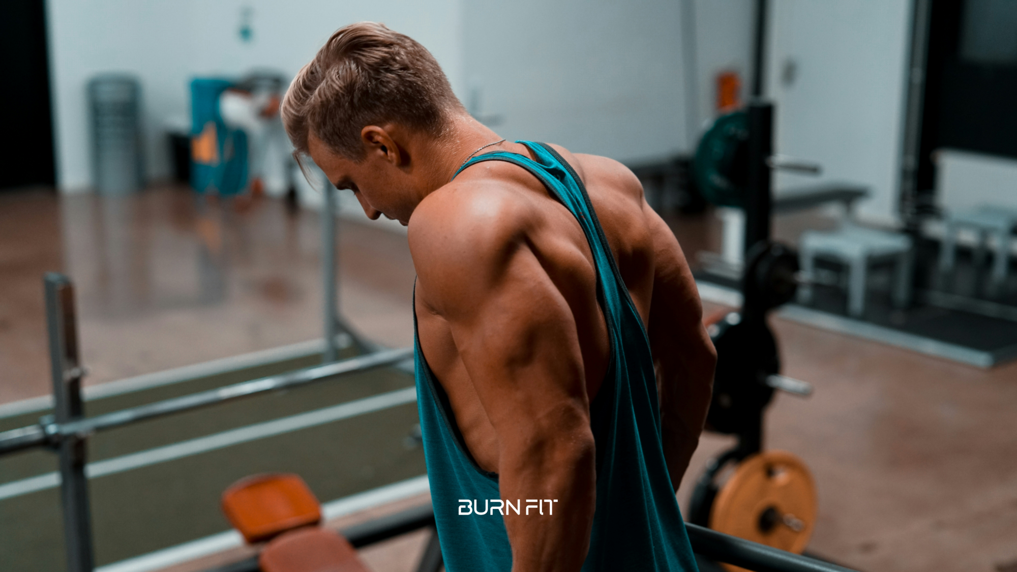 Muscular man showing defined back and shoulder muscles in a gym after an upper body workout. Fitness image highlighting lat development, rear delts, traps, and overall back aesthetics.
