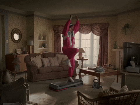 빈티지한 거실에서 핑크색 트레이닝복을 입고 스텝박스 운동을 즐겁게 수행하는 모습, 재미있는 홈트 루틴 컨셉